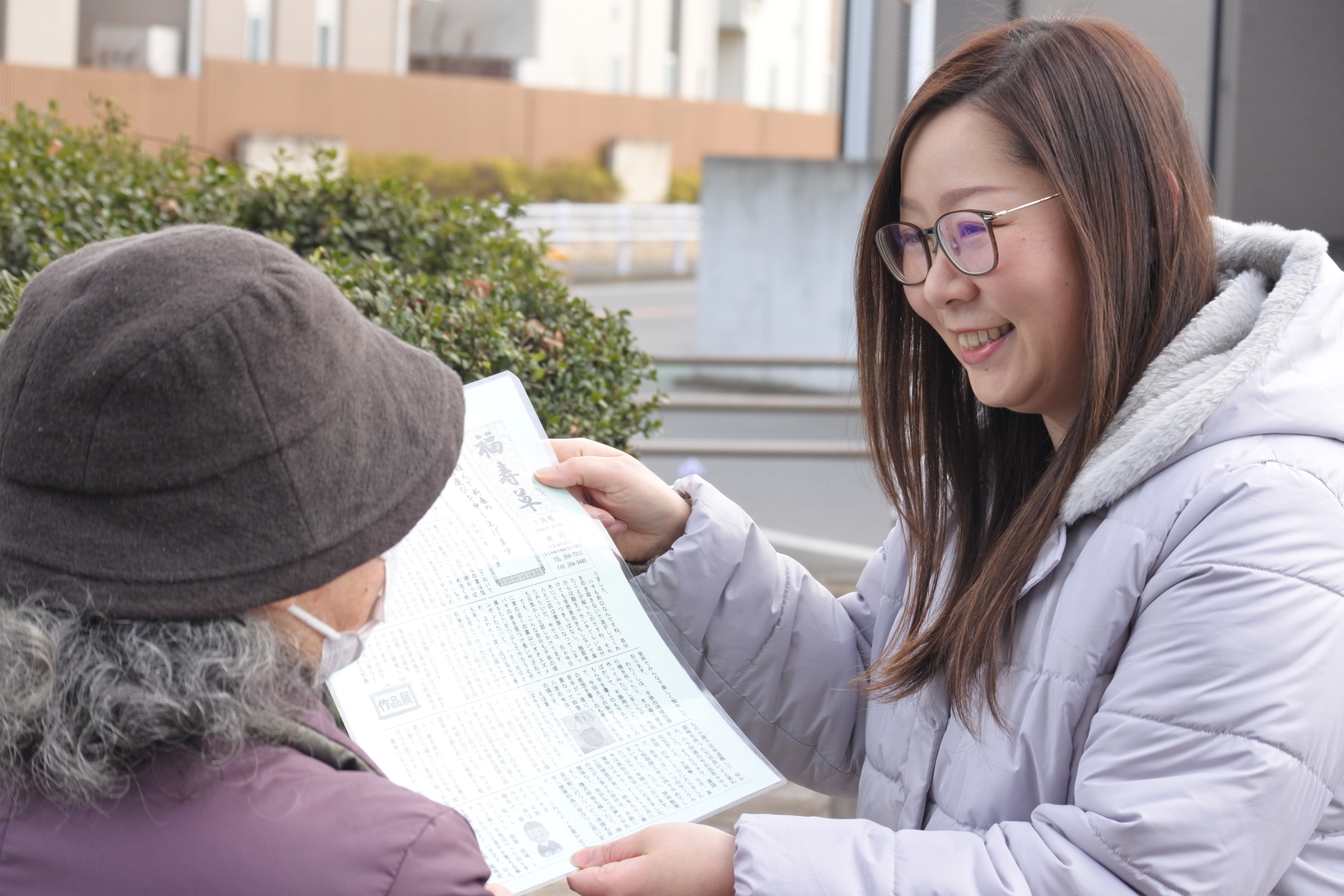民生委員が高齢者に情報誌「福寿草」を手渡ししている様子